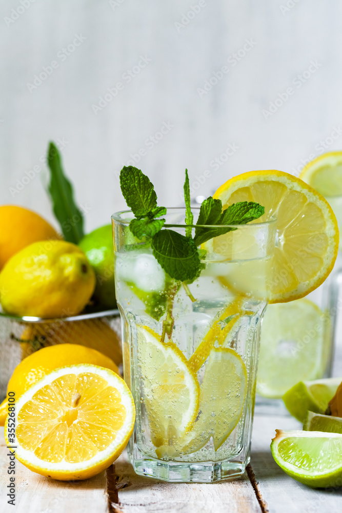 Concept of summer refreshing healthy alcohol free homemade lemonade with fresh pepper mint, limes and lemons. Low calories cold detox beverage. Wooden background, closeup. Copy space for text Concept of summer refreshing healthy alcohol free homemade lemonade with fresh pepper mint, limes and lemons. Low calories cold detox beverage. Wooden background, closeup. Copy space for text