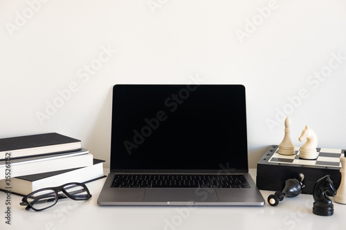 Workspace desk. Top view office desk with laptop, pencils and chess on white color background.