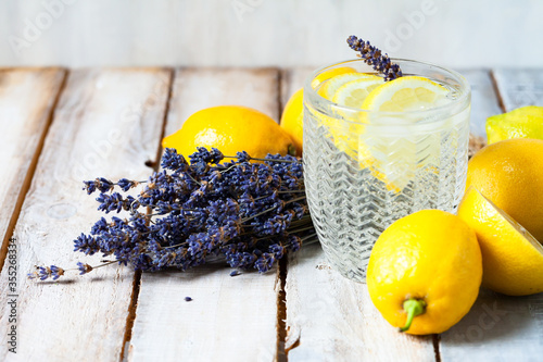 Concept of summer refreshing healthy alcohol free homemade lemonade with lemons and lavender. Low calories cold detox beverage. Wooden background, closeup. Copy space for text