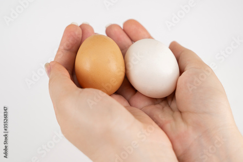 White and gray chicken eggs in a hand on a white background