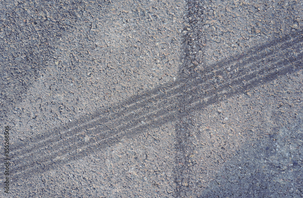 Naklejka premium Asphalt texture with white line and tire marks. Smooth asphalt road. Tarmac dark grey grainy road background.Top view