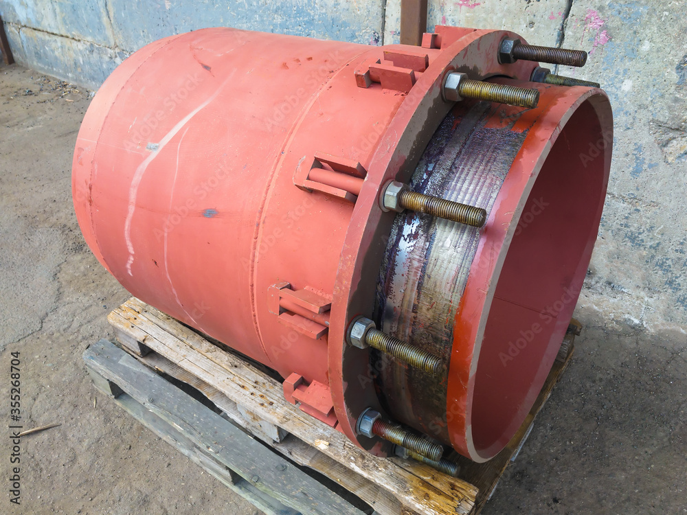 Red gland expansion joint for heating main on concrete floor. Heat and power concept. Red gland expansion joint for heating main on concrete floor. Heat and power concept.
