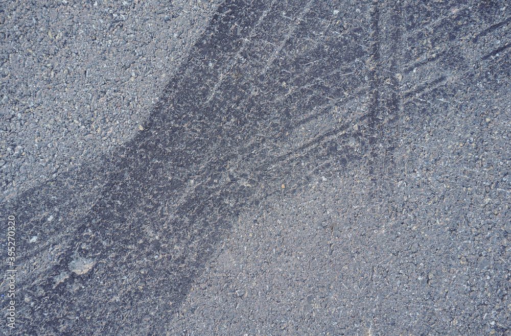 Naklejka premium Asphalt texture with white line and tire marks. Smooth asphalt road. Tarmac dark grey grainy road background.Top view