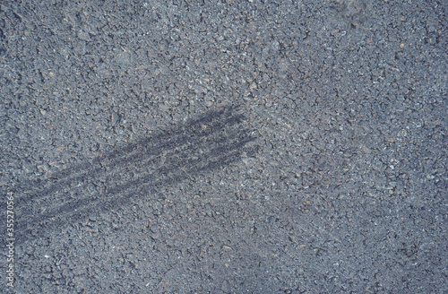 Asphalt texture with white line and tire marks.  Smooth asphalt road. Tarmac dark grey grainy road background.Top view