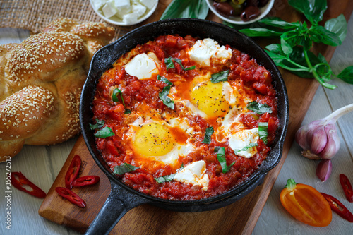 Shakshuka. Fried eggs in tomato sauce, with tomatoes and hot peppers, in a cast-iron frying pan.
