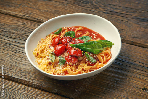 Homemade, Italian pasta - spaghetti with tomatoes and cheese in a bowl on a wooden background