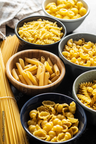 Various types of raw italian pasta in bowls.