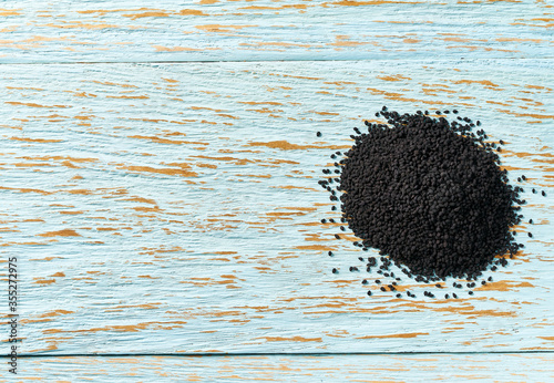 black cumin on a blue wooden table, top view with copy space. photo