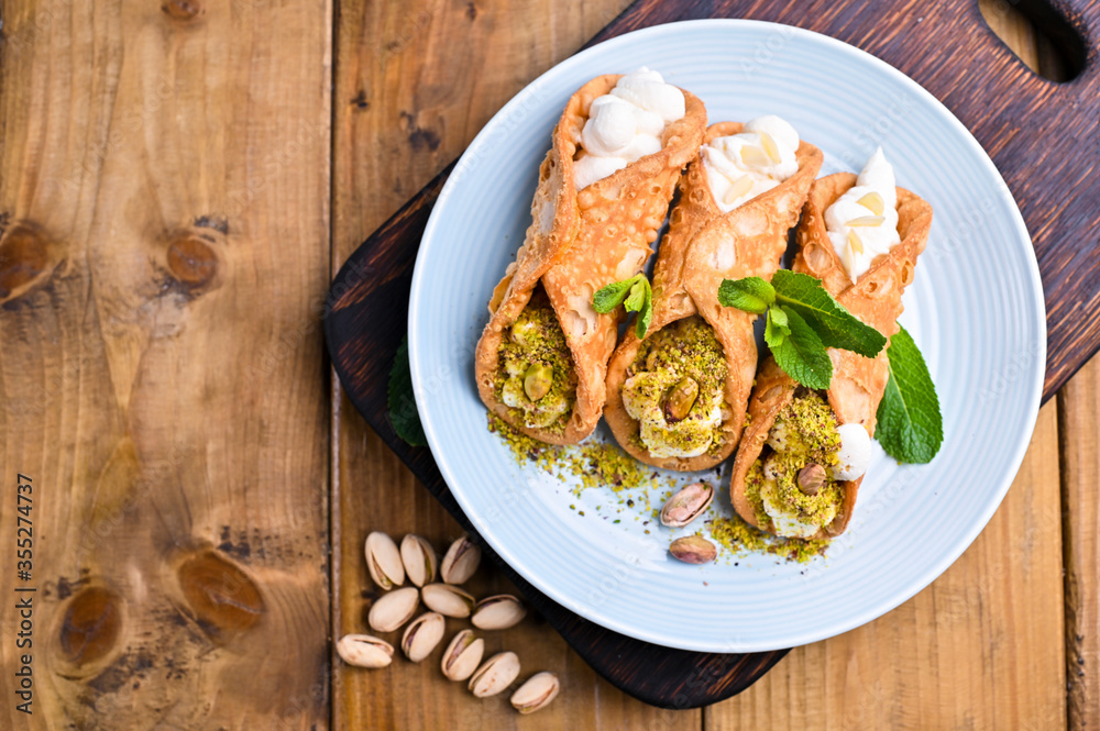 Cannoli Sicily. Traditional Italian sweet with ricotta and various fillings. Food on a wooden cutting board.