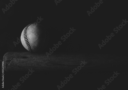Moody baseball background with old ball and bat in black and white with copy space.