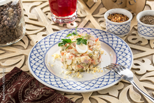 Traditional Russian salad Olivier with egg on top on wooden table