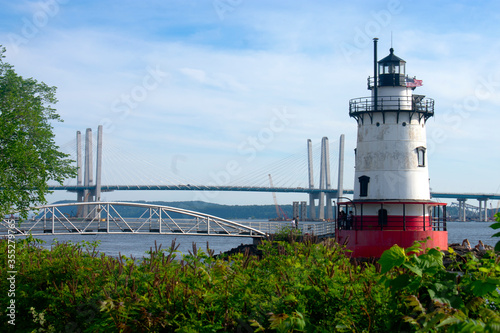 Short, red and white lighthouse situated in Westchester County on the Hudson River with the rebuilt Tappan Zee Bridge in the background.