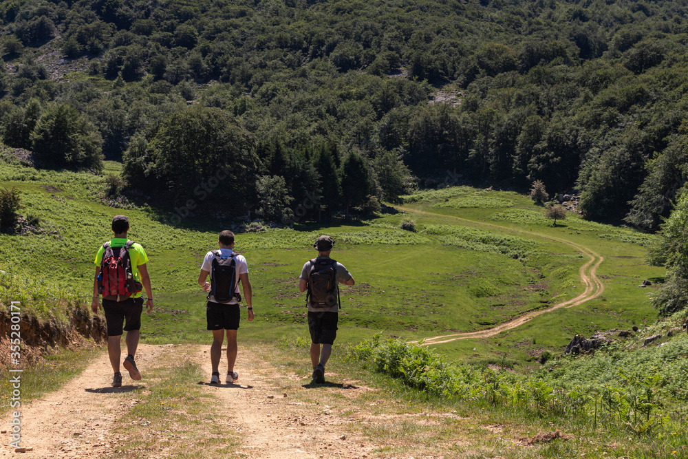 varias personas caminan por senderos en el monte gorbea en un dia soleado con pocas nubes y caminos de piedras , vistas a la montaña