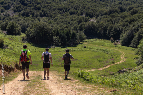 varias personas caminan por senderos en el monte gorbea en un dia soleado con pocas nubes y caminos de piedras , vistas a la montaña