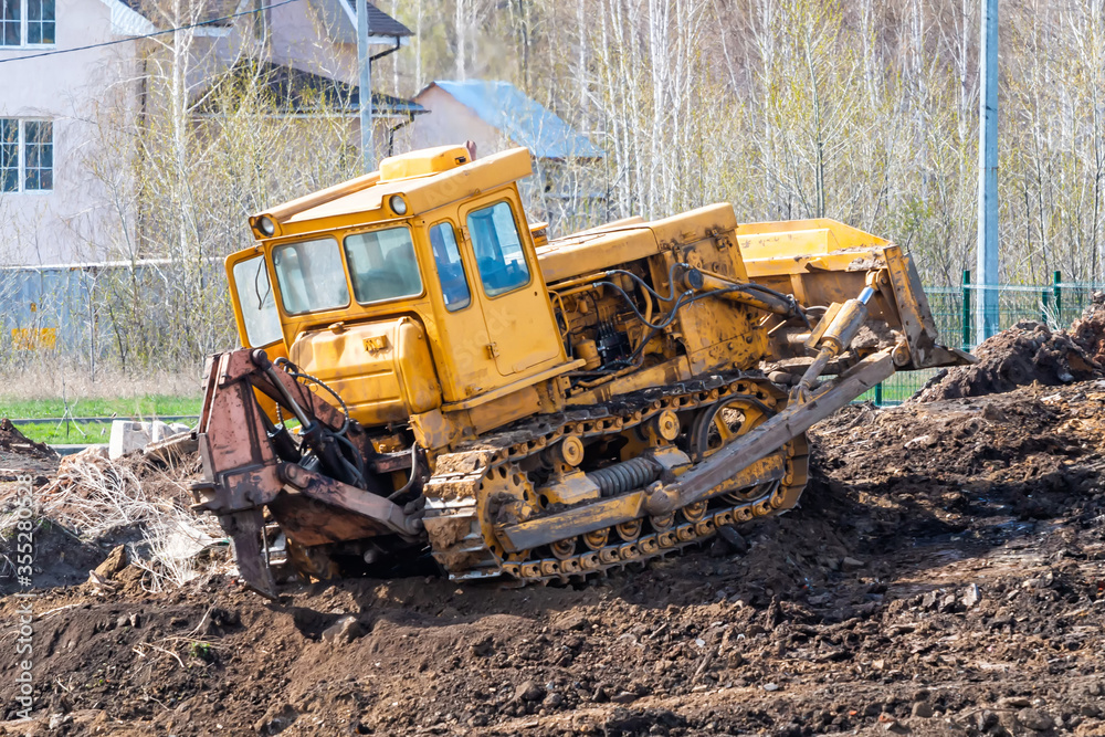 Yellow bulldozer leveling the ground at a construction site