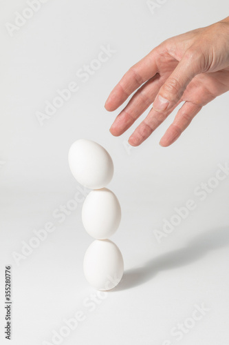 Male hand making a pile of eggs. Balance concept.