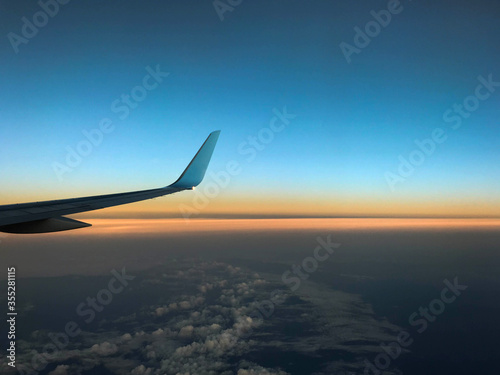 Curved wing tip of a commercial aircraft against a colourful dawn sky. No people. Space for copy.