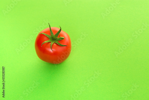Single real tomato seen at its top on a green background