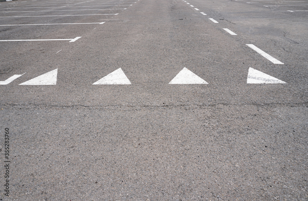 Dark asphalt road with marking lines. Tarmac texture. White disabled sign on a empty parking lot. Black tarmac texture with road marking Dark asphalt road with marking lines. Tarmac texture. White disabled sign on a empty parking lot. Black tarmac texture with road marking
