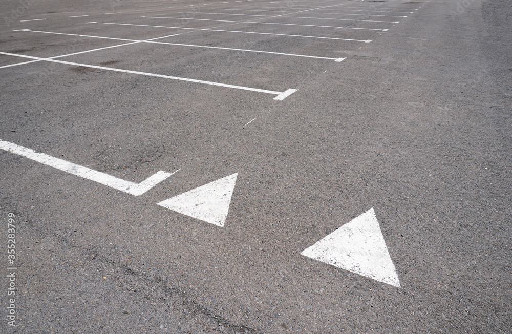 Dark asphalt road with marking lines. Tarmac texture. White disabled sign on a empty parking lot. Black tarmac texture with road marking Dark asphalt road with marking lines. Tarmac texture. White disabled sign on a empty parking lot. Black tarmac texture with road marking