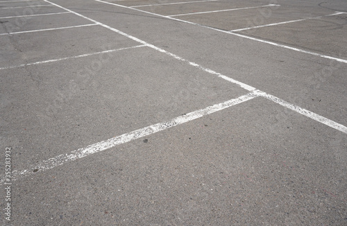 Dark asphalt road with marking lines. Tarmac texture. White disabled sign on a empty parking lot. Black tarmac texture with road marking 