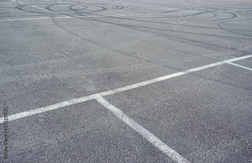 Dark asphalt road with marking lines. Tarmac texture. White disabled sign on a empty parking lot. Black tarmac texture with road marking 