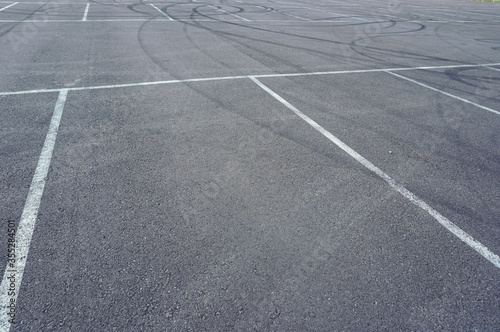 Dark asphalt road with marking lines. Tarmac texture. White disabled sign on a empty parking lot. Black tarmac texture with road marking 