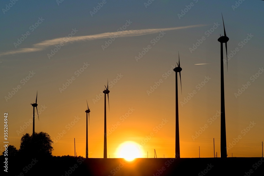 Fototapeta premium Field of wind generators at sunset. Great sun on the horizon.