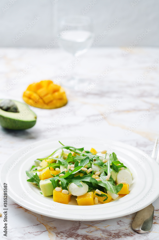 Avocado mango arugula pine nuts Mozzarella salad in a plate Avocado mango arugula pine nuts Mozzarella salad in a plate
