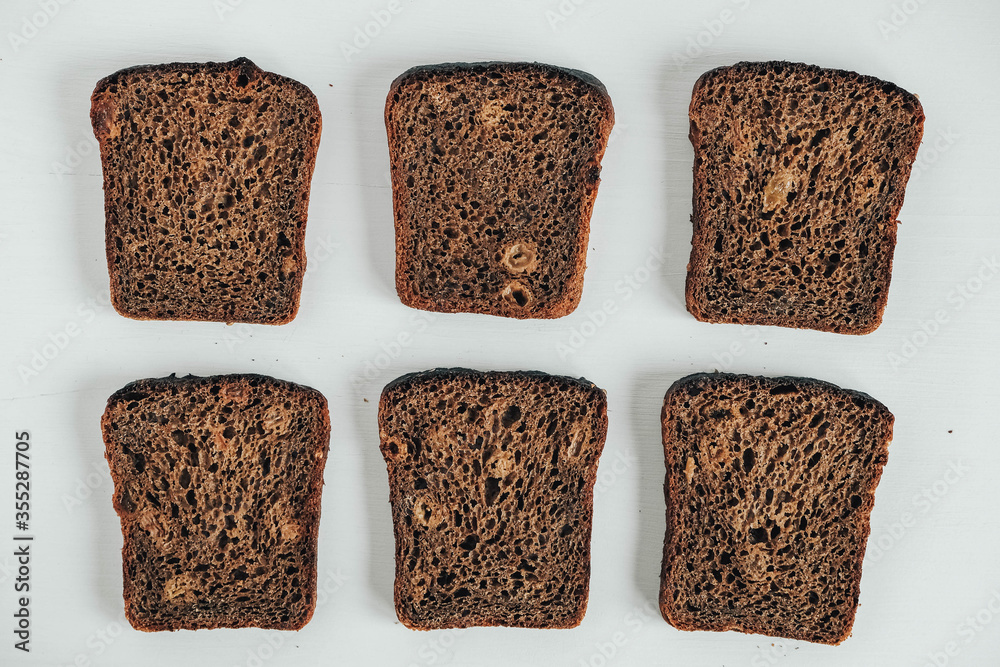 Slices of fresh brown bread with raisins on a white wooden background. Top view. Copy, empty space for text Slices of fresh brown bread with raisins on a white wooden background. Top view. Copy, empty space for text