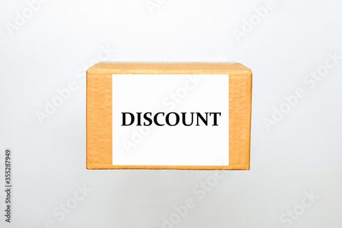 Cardboard box with sticker layout and Discount text on a white background with copy space. The concept of gifts in a box with a form and online delivery of goods