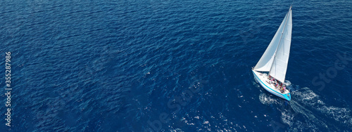 Obraz na płótnie Aerial drone ultra wide photo of beautiful sail boat with white sails sailing open ocean deep blue sea w salonie