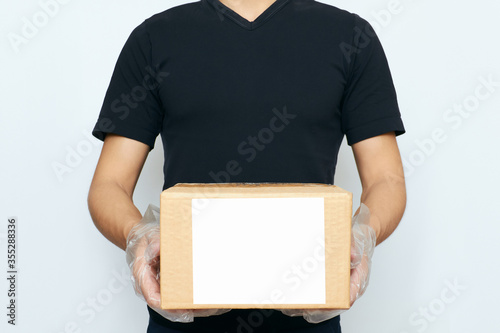 A delivery man holding a box with copy space on a white background. The concept of online ordering, business purchasing, and courier delivery to your home