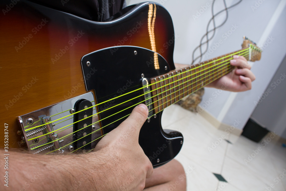 Fototapeta premium Man hands playing chords on electric guitar with yellow strings with white background.