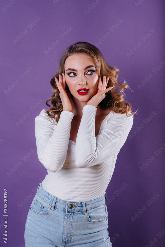 A young beautiful girl shows emotions and smiles in the Studio on a purple background. Girls for advertising