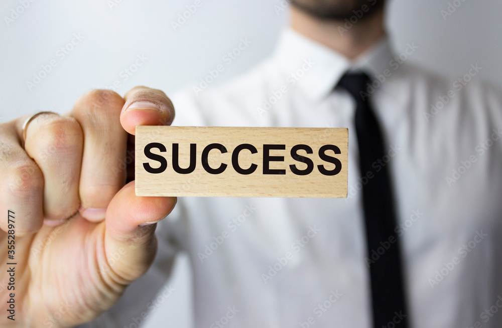 The inscription success on a wooden block in the hands of a businessman. Business concept for process growth success. The inscription success on a wooden block in the hands of a businessman. Business concept for process growth success.