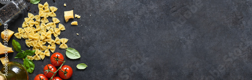 Raw farfolle with tomato and basil on a black background. Top view. Ingredients for making pasta photo