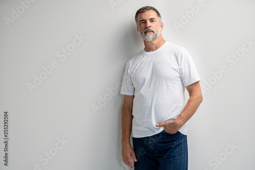 Portrait of smiling mature man standing on white background. © opolja