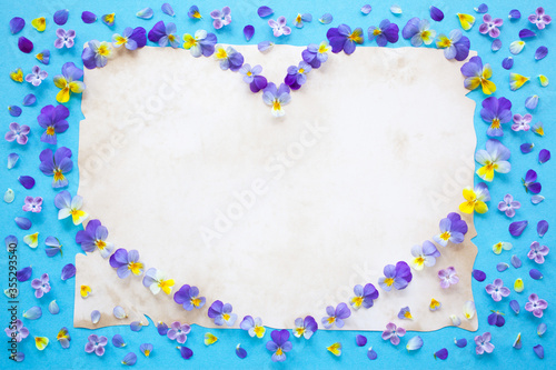 Floral background, greeting card, heart made of pansies, violets, paper and empty space for text.
