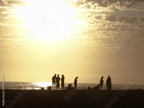 Silhouette of family friends people dog on beach sunset