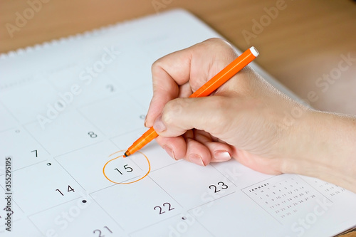 Female hand writing in calendar on 15th day of ovulation