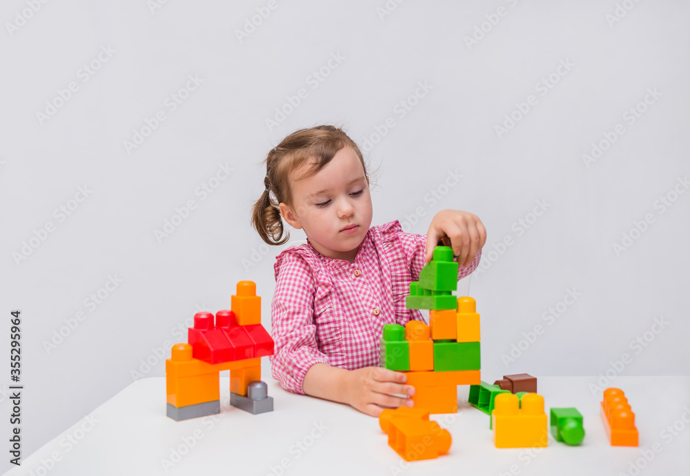Little girl learn to build from a constructor on a white background. Little girl learn to build from a constructor on a white background.