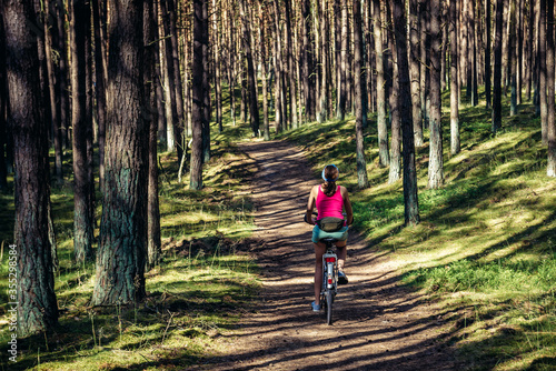 Woman rides bike in Wolin National Park on Wolin - Baltic Sea island in Poland photo