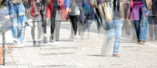 Crowd of abstract people walking in the shopping pedestrian zone, multiple exposure and motion blur, panoramic format, copy space