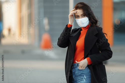 Portrait of beautiful woman walking on the street wearing protective mask as protection against infectious diseases.