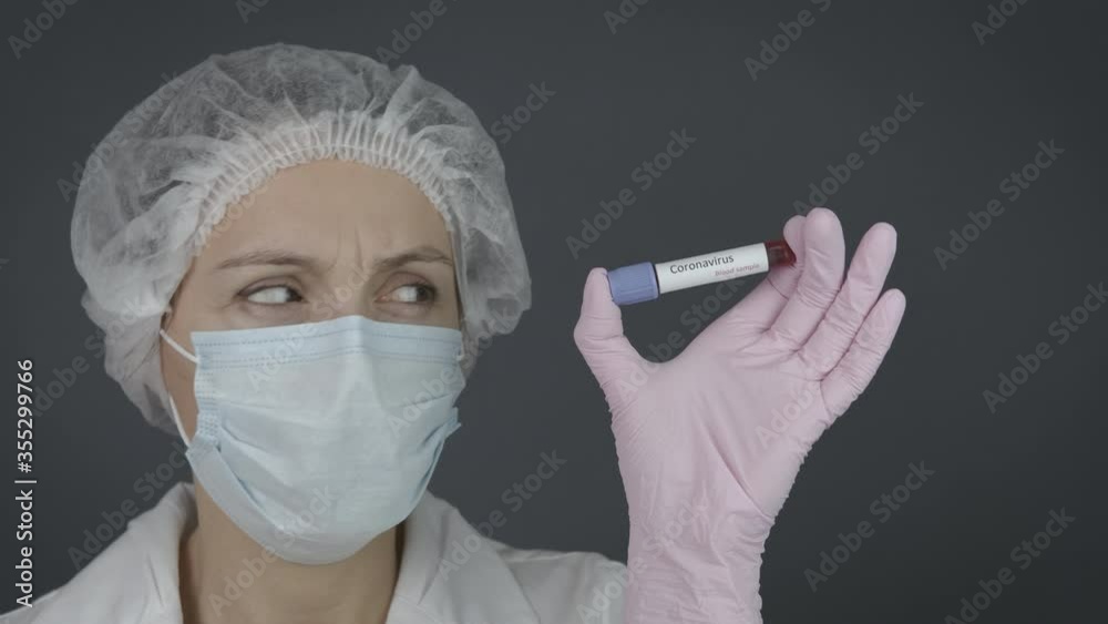 Biology tube with blood. Frightened female laboratory assistant with a test tube of coronavirus. Biology tube with blood. Frightened female laboratory assistant with a test tube of coronavirus.