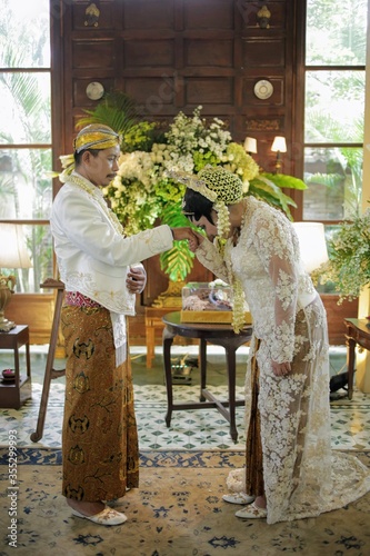 Beautiful indonesian bride kissing groom hands  after wedding ceremony for symbol loyalty.