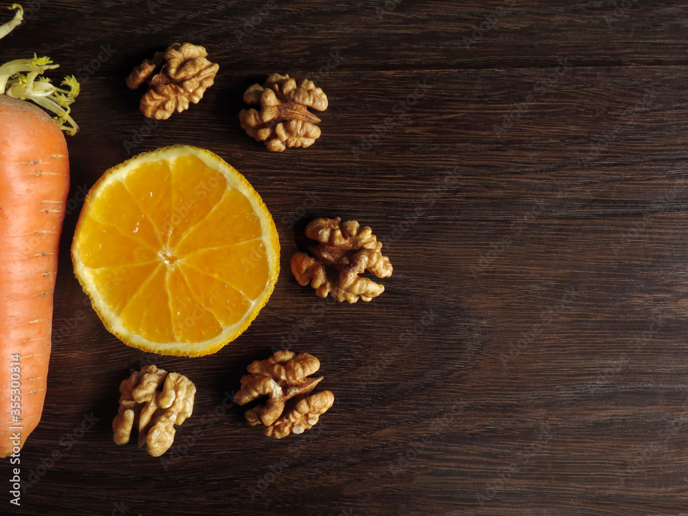 Carrots, orange and walnuts on a dark wooden background, top view. Ingredients for Carrot Cake Carrots, orange and walnuts on a dark wooden background, top view. Ingredients for Carrot Cake