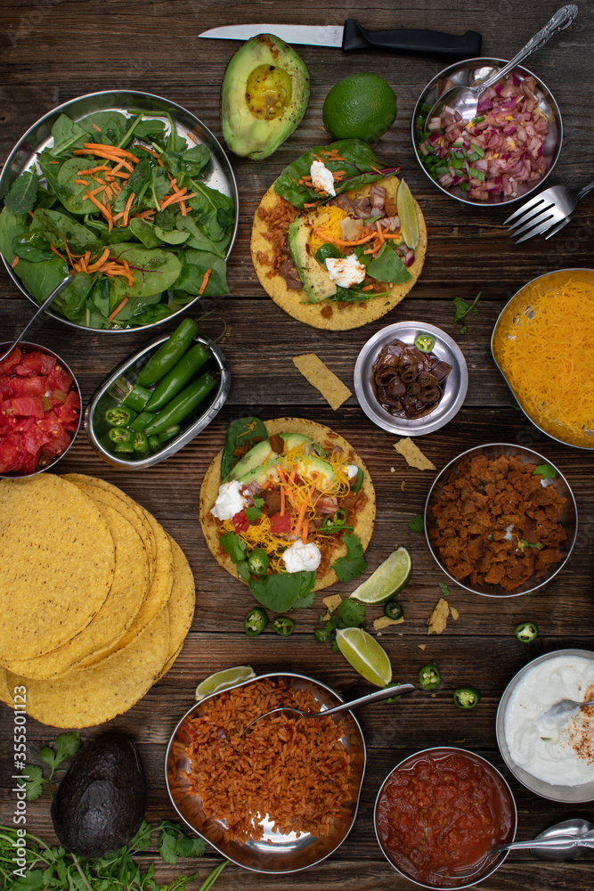 Vegetarian corn tostada with a variety of side toppings on wooden table Vegetarian corn tostada with a variety of side toppings on wooden table
