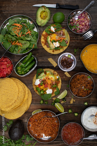 Vegetarian corn tostada with a variety of side toppings on wooden table